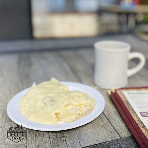 Breakfast_Thelmas_copyright_ExploreBigBearLake_dot_com_biscuit and gravy on white plate with coffee mug in background